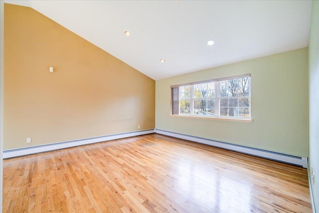 empty room featuring light hardwood / wood-style flooring, vaulted ceiling, and a baseboard heating unit