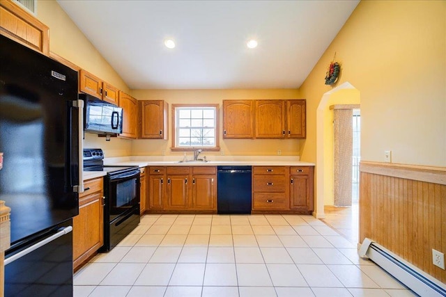 kitchen with vaulted ceiling, sink, black appliances, a baseboard radiator, and light tile patterned flooring