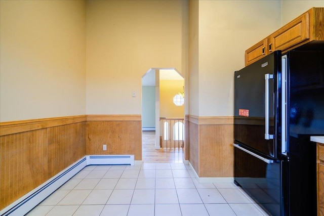 kitchen featuring black fridge, light tile patterned floors, a high ceiling, and a baseboard radiator