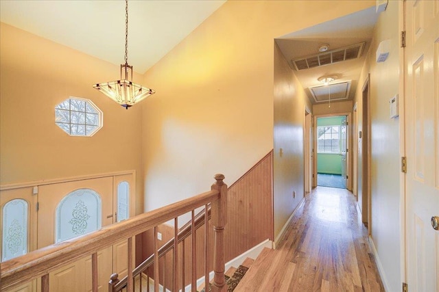 hall with a wealth of natural light, light hardwood / wood-style flooring, and high vaulted ceiling