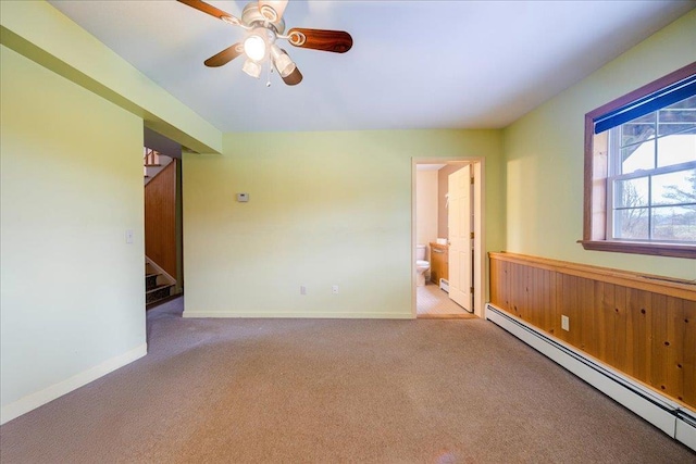 empty room with ceiling fan, light colored carpet, and a baseboard heating unit