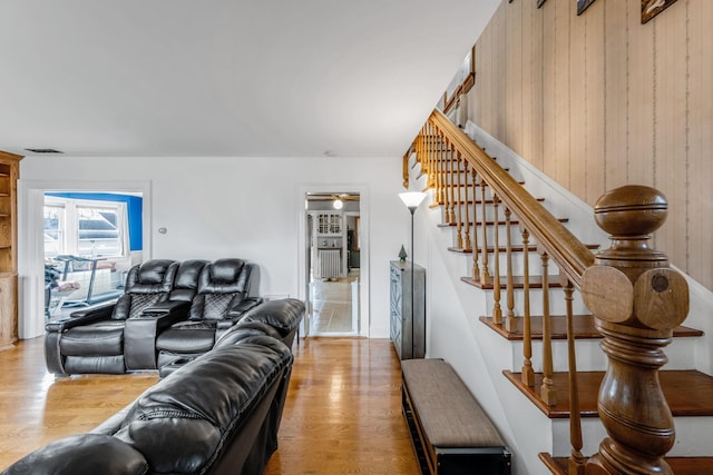 living room featuring light wood-type flooring, ceiling fan, and wooden walls