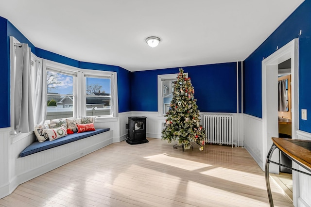 living area featuring radiator heating unit, light wood-type flooring, and a wood stove