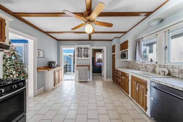 kitchen featuring appliances with stainless steel finishes, backsplash, radiator, sink, and tile counters