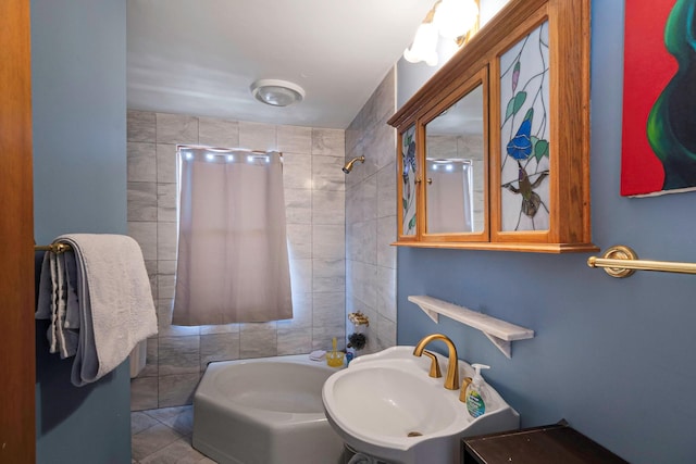 bathroom with tile patterned floors, tiled shower / bath, sink, and tile walls