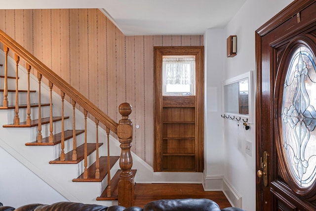 foyer entrance with hardwood / wood-style floors and wooden walls