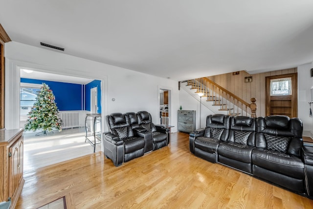 living room featuring hardwood / wood-style flooring, wood walls, radiator, and a wealth of natural light