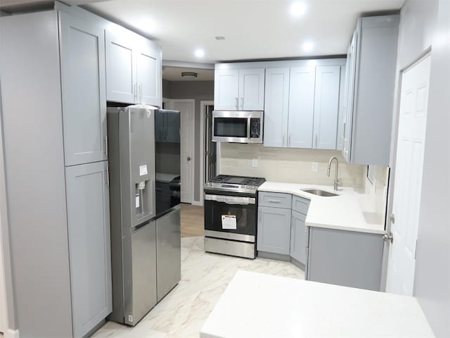 kitchen featuring backsplash, gray cabinets, sink, and appliances with stainless steel finishes