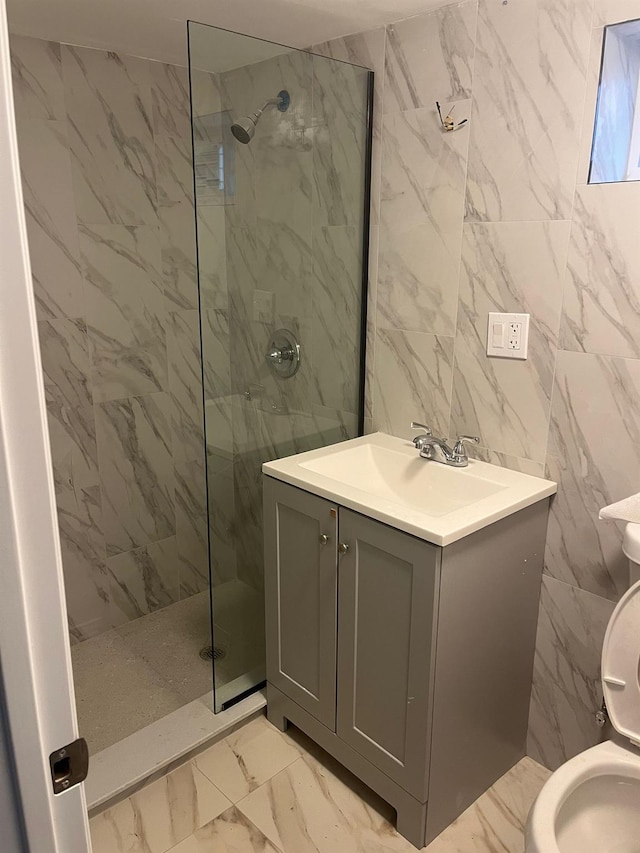 bathroom with toilet, a tile shower, tile walls, and vanity