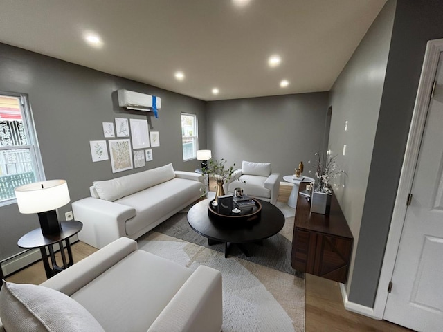 living area featuring baseboards, a wall unit AC, wood finished floors, and recessed lighting