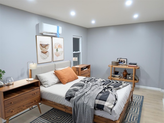 bedroom featuring baseboards, light wood-type flooring, a wall unit AC, and recessed lighting