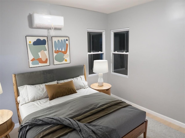 bedroom featuring baseboards, wood finished floors, and a wall mounted AC