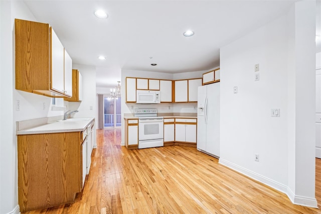 kitchen with white cabinetry, sink, light hardwood / wood-style flooring, a notable chandelier, and white appliances