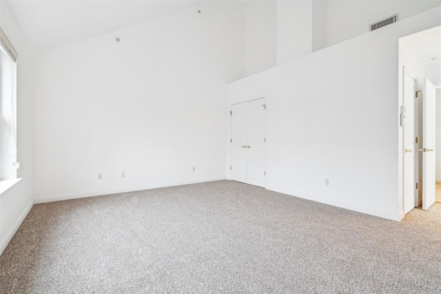 carpeted spare room with a towering ceiling