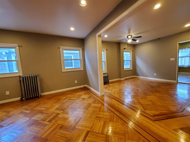 empty room with a wealth of natural light, radiator heating unit, and light parquet flooring