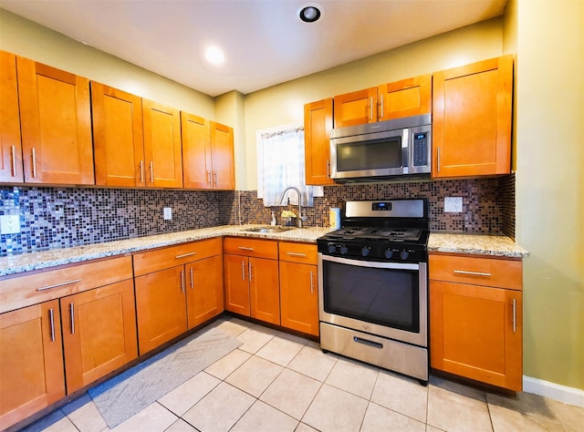 kitchen featuring decorative backsplash, appliances with stainless steel finishes, light tile patterned floors, and sink