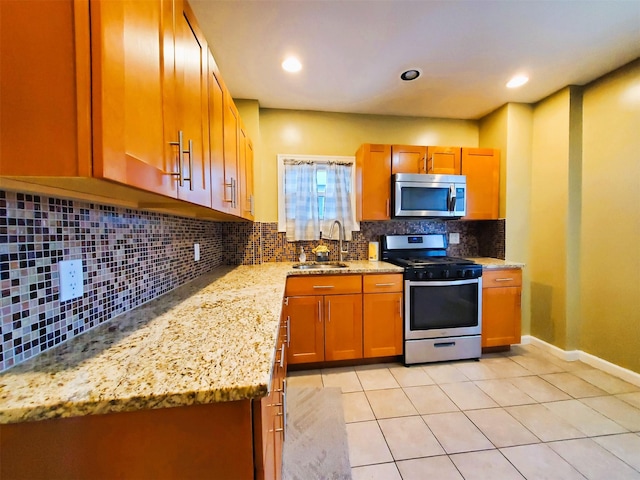 kitchen with backsplash, light stone countertops, sink, and appliances with stainless steel finishes