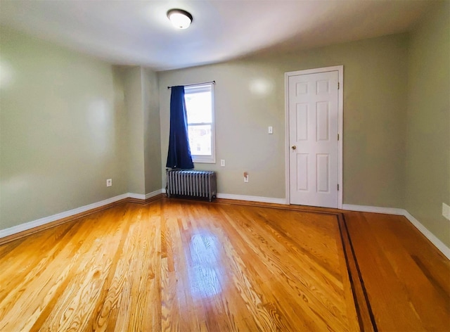 spare room featuring radiator and hardwood / wood-style flooring