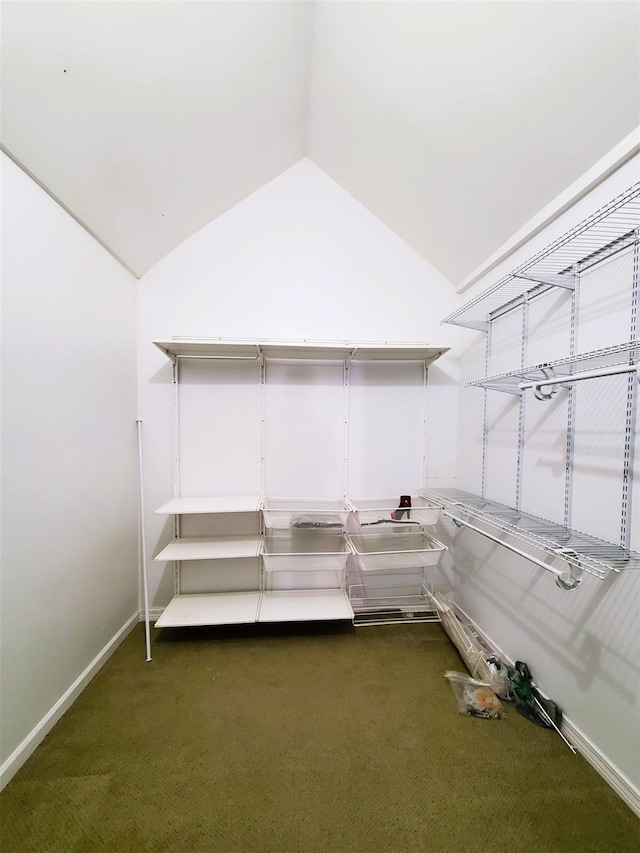 walk in closet with dark colored carpet and vaulted ceiling