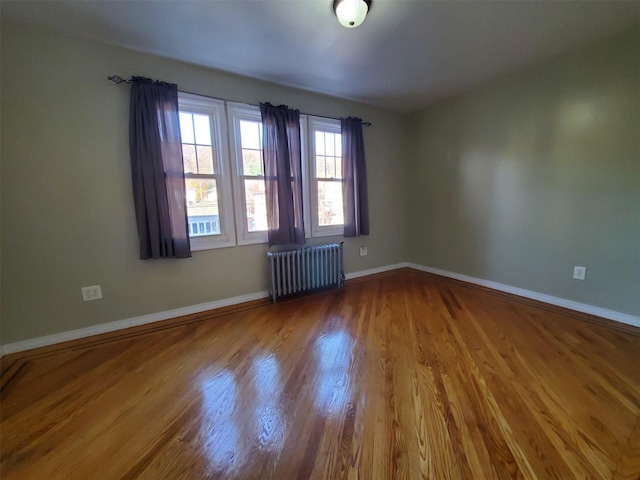 unfurnished room with radiator heating unit and hardwood / wood-style floors