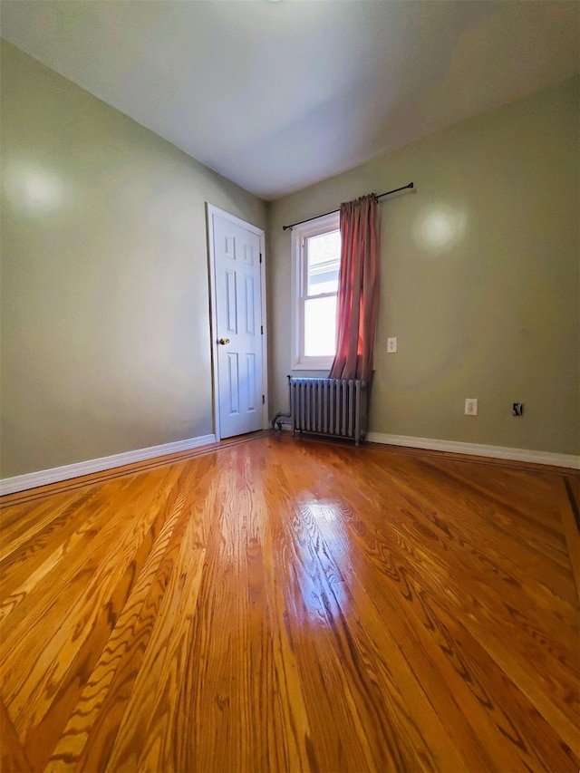 empty room featuring radiator heating unit and light hardwood / wood-style floors