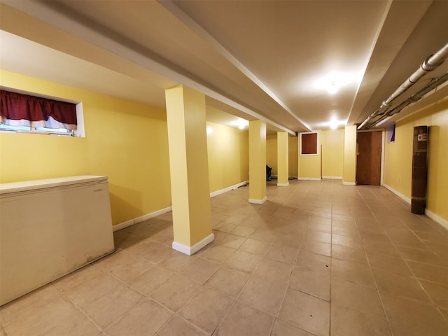 basement featuring light tile patterned flooring and fridge