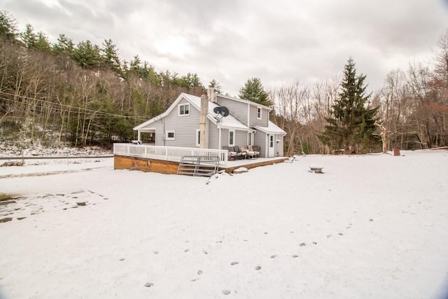 snow covered back of property featuring a wooden deck