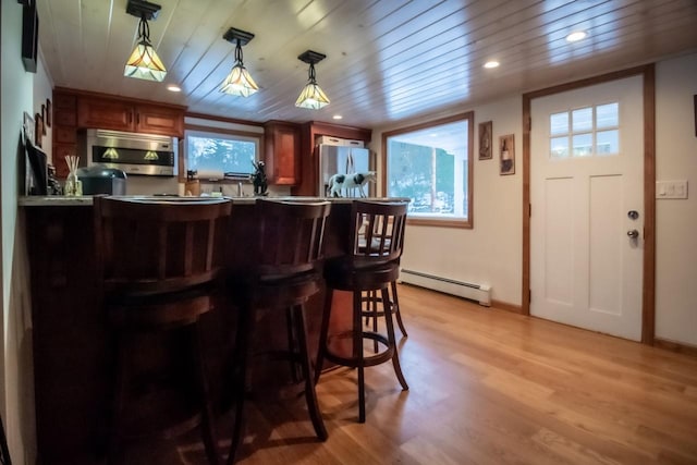 bar featuring hanging light fixtures, light wood-type flooring, stainless steel appliances, and baseboard heating