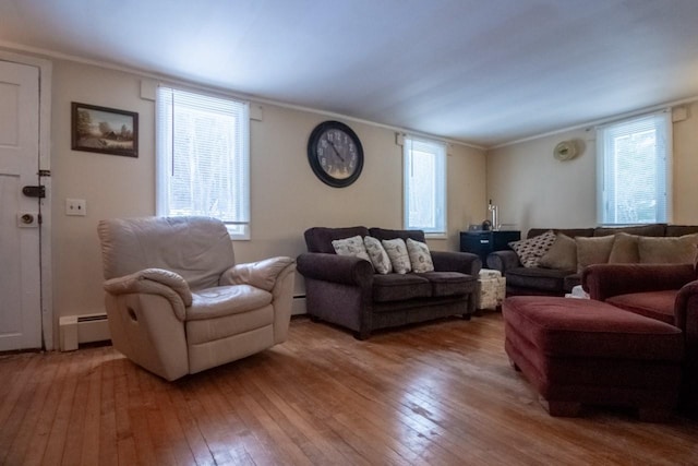 living room featuring a wealth of natural light, crown molding, wood-type flooring, and a baseboard heating unit