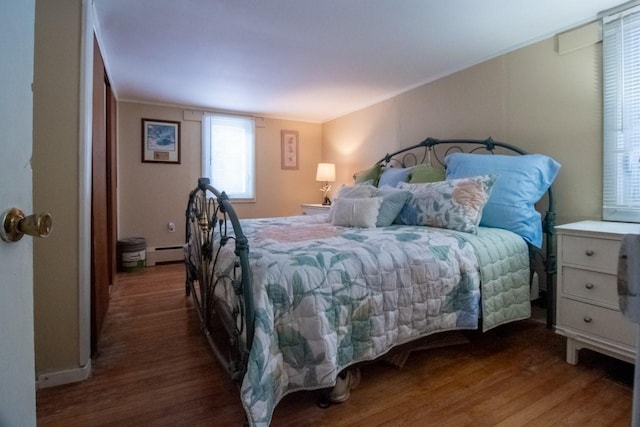 bedroom with dark hardwood / wood-style floors and baseboard heating