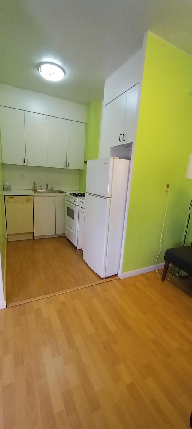 kitchen with white cabinetry, light hardwood / wood-style floors, and white appliances