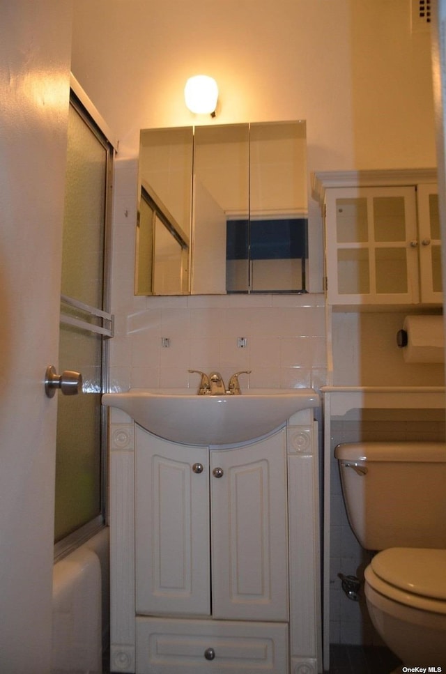 full bathroom with decorative backsplash, vanity, toilet, and combined bath / shower with glass door