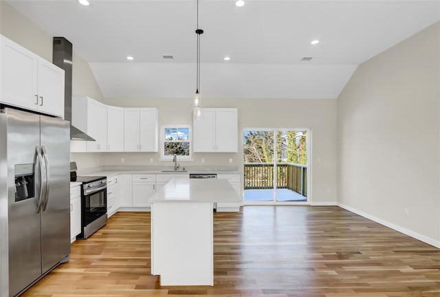 kitchen with wall chimney range hood, white cabinetry, hanging light fixtures, stainless steel appliances, and a kitchen island