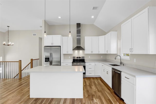 kitchen featuring a kitchen island, appliances with stainless steel finishes, sink, hanging light fixtures, and wall chimney range hood