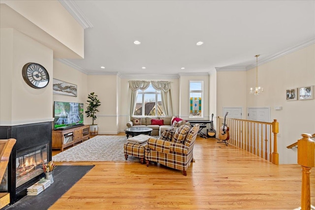 living room with light hardwood / wood-style floors, an inviting chandelier, and crown molding