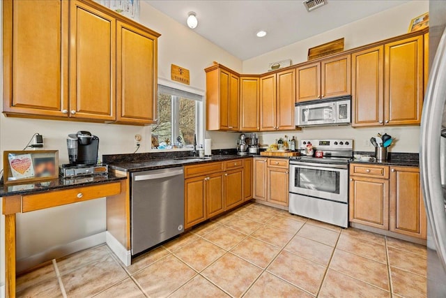 kitchen with light tile patterned flooring, sink, appliances with stainless steel finishes, and dark stone counters