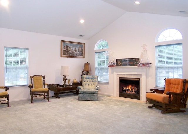 sitting room featuring carpet flooring, a tiled fireplace, plenty of natural light, and lofted ceiling