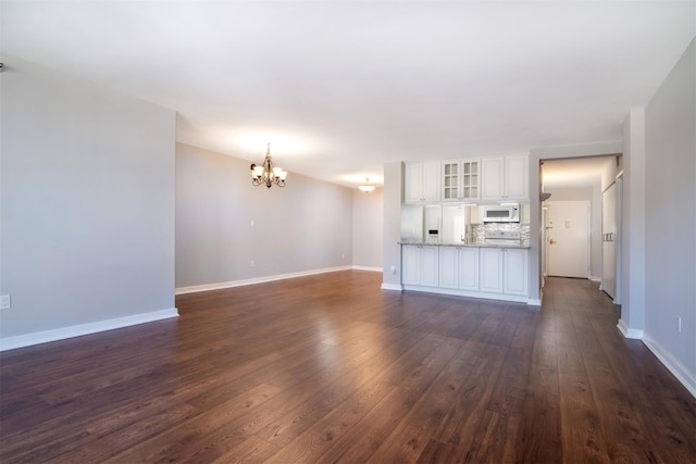 unfurnished living room featuring dark hardwood / wood-style flooring and a chandelier