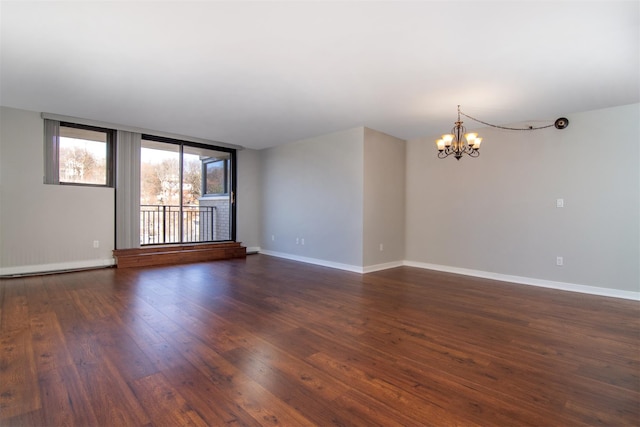 spare room with dark hardwood / wood-style flooring and a chandelier