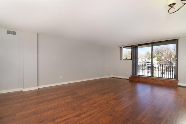 empty room featuring a notable chandelier and dark wood-type flooring