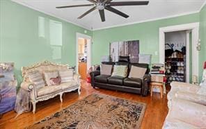 living room featuring hardwood / wood-style floors, ceiling fan, and crown molding