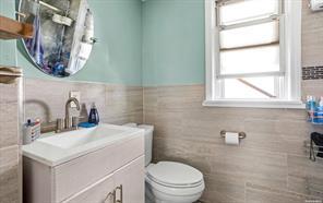 bathroom featuring vanity, toilet, and tile walls