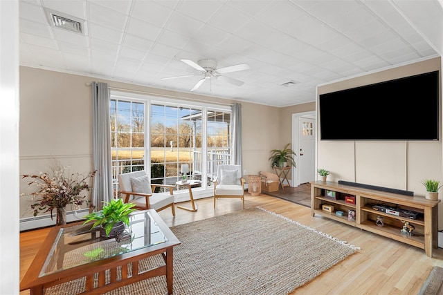 living room featuring ceiling fan, ornamental molding, a baseboard heating unit, and hardwood / wood-style flooring