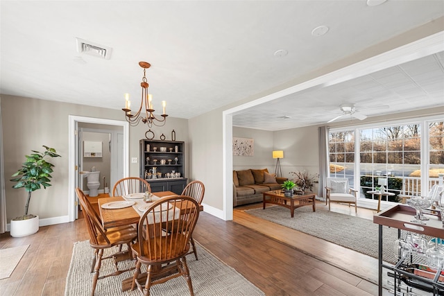 dining space with hardwood / wood-style flooring and ceiling fan with notable chandelier