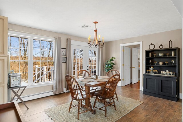 dining area featuring baseboard heating, french doors, dark wood-type flooring, and an inviting chandelier