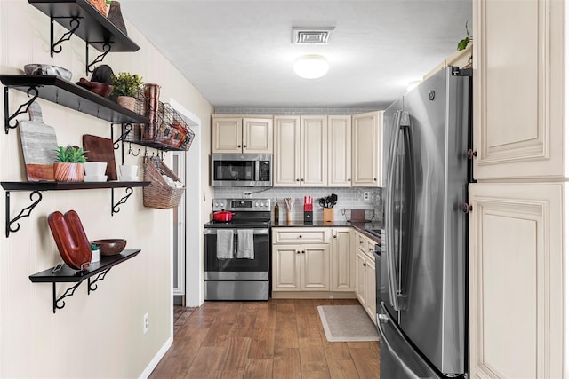 kitchen featuring dark hardwood / wood-style floors, tasteful backsplash, stainless steel appliances, and cream cabinets