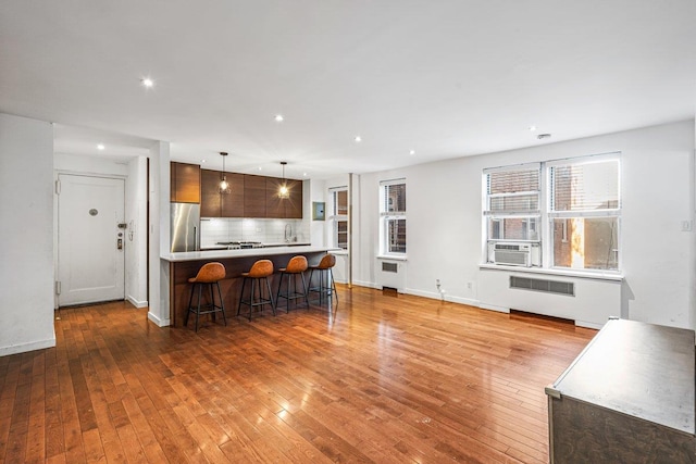 kitchen featuring decorative backsplash, stainless steel fridge, a breakfast bar, and light hardwood / wood-style flooring