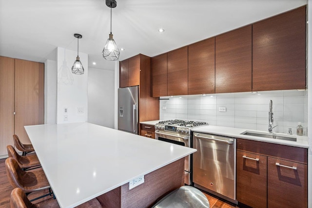 kitchen with a kitchen breakfast bar, sink, hardwood / wood-style floors, and appliances with stainless steel finishes