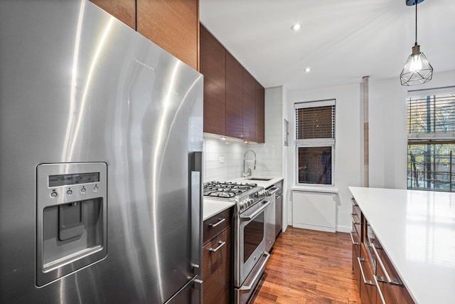 kitchen featuring sink, appliances with stainless steel finishes, tasteful backsplash, dark brown cabinets, and light hardwood / wood-style floors