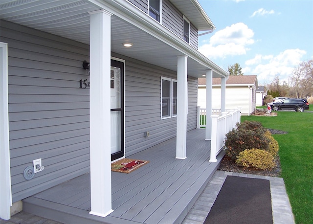 wooden terrace with a lawn and covered porch